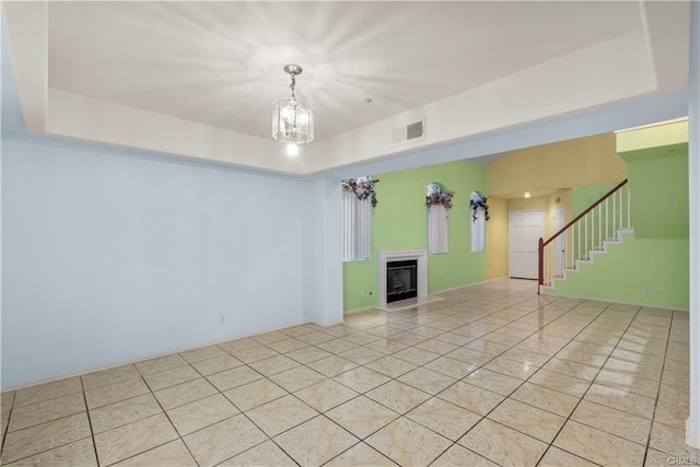 unfurnished living room with visible vents, a raised ceiling, a fireplace, and stairs