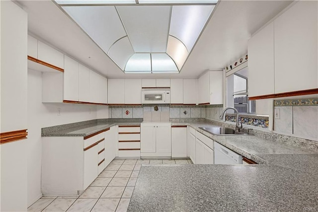 kitchen featuring white appliances, light tile patterned floors, a sink, white cabinets, and tasteful backsplash