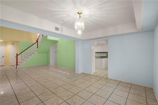 empty room featuring light tile patterned floors, visible vents, stairs, and an inviting chandelier