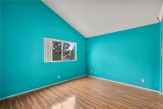 spare room featuring baseboards, lofted ceiling, and wood finished floors