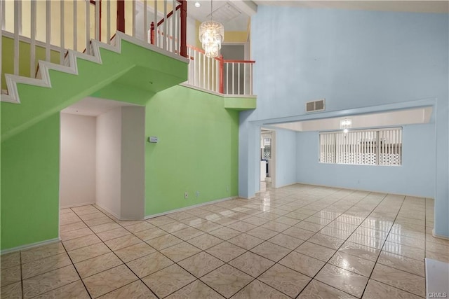 unfurnished living room featuring visible vents, baseboards, a high ceiling, an inviting chandelier, and tile patterned floors