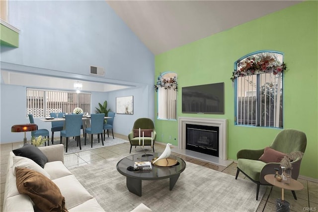 tiled living room with visible vents, a fireplace with raised hearth, and high vaulted ceiling