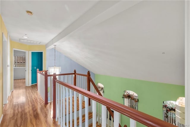 hall featuring vaulted ceiling with beams, attic access, an upstairs landing, wood finished floors, and a notable chandelier