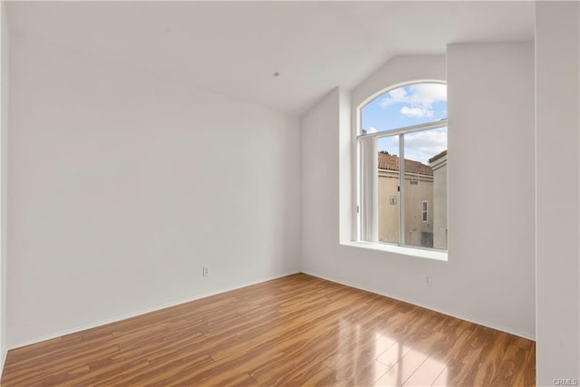 spare room with lofted ceiling and wood finished floors