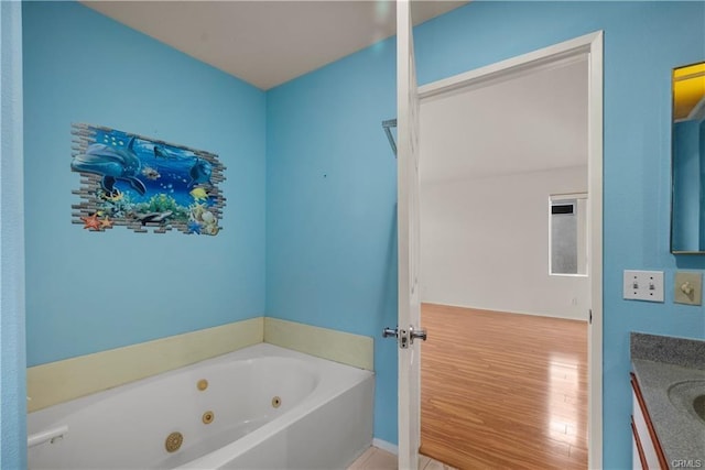 full bath with wood finished floors, vanity, and a whirlpool tub