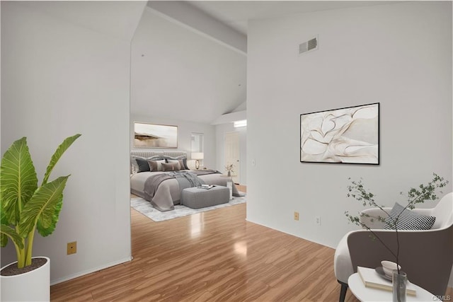 bedroom featuring wood finished floors, visible vents, and high vaulted ceiling