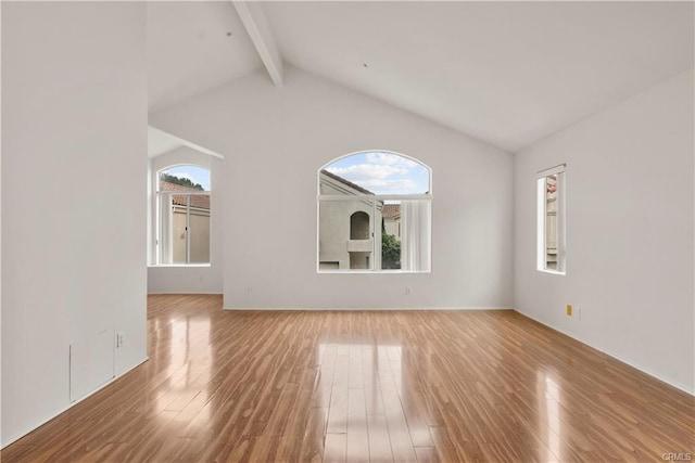 unfurnished room featuring wood finished floors and vaulted ceiling with beams