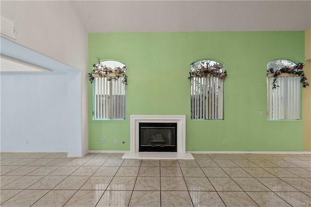 unfurnished living room with light tile patterned floors, visible vents, a fireplace, and baseboards