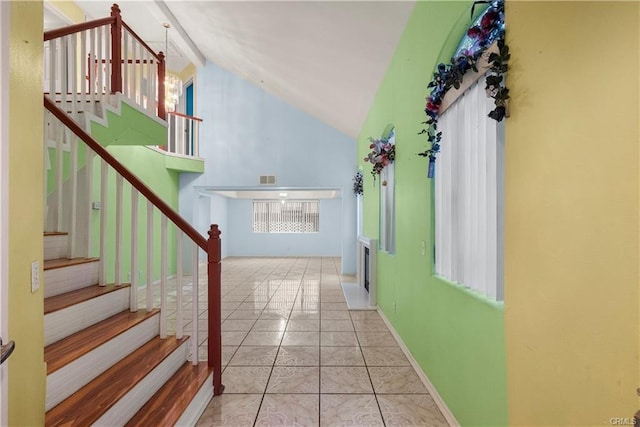 stairs featuring tile patterned flooring, baseboards, visible vents, and high vaulted ceiling