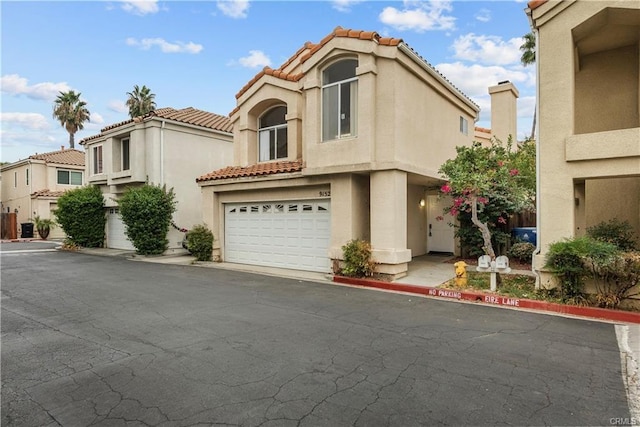 mediterranean / spanish home featuring stucco siding, an attached garage, and a tile roof