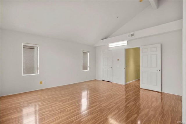 unfurnished room with visible vents, light wood-style flooring, and high vaulted ceiling