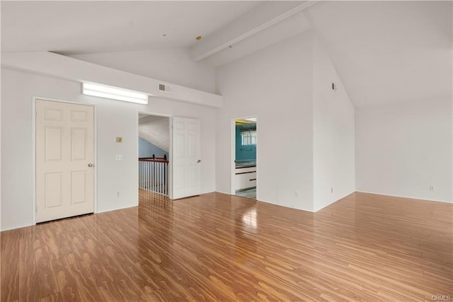 unfurnished room featuring beam ceiling, wood finished floors, visible vents, and high vaulted ceiling