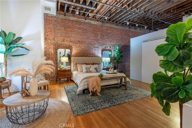 bedroom featuring wood finished floors and brick wall