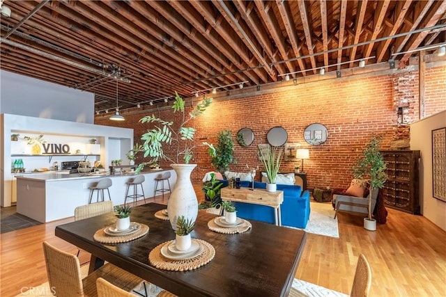 dining room with rail lighting, wood finished floors, and brick wall