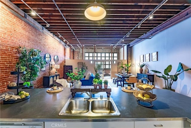 kitchen with dark countertops, brick wall, and a sink