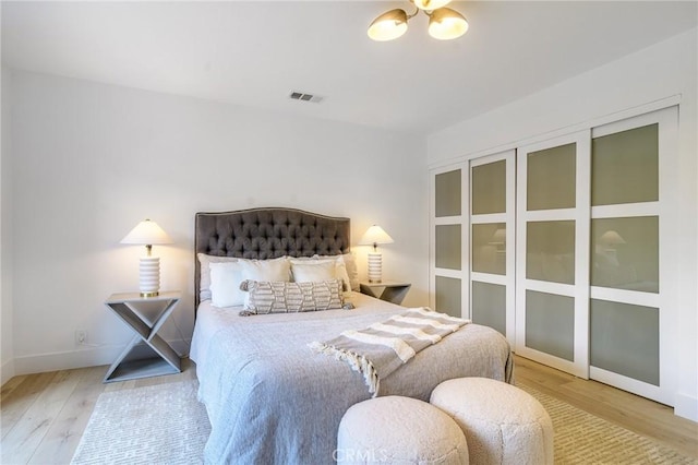 bedroom featuring wood finished floors, visible vents, a chandelier, and baseboards