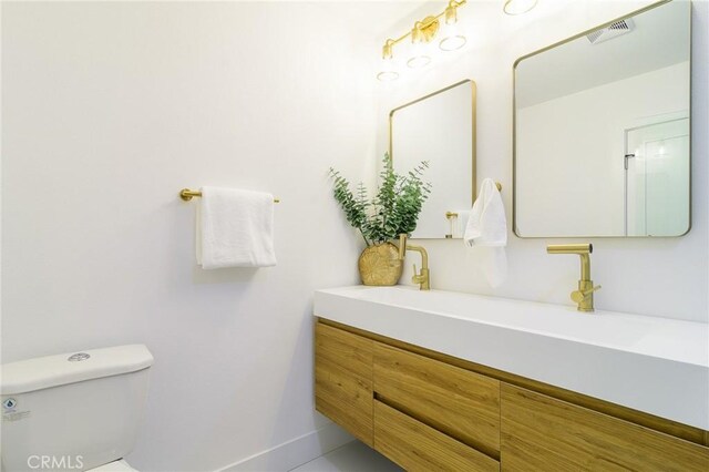 bathroom featuring vanity, toilet, baseboards, and visible vents