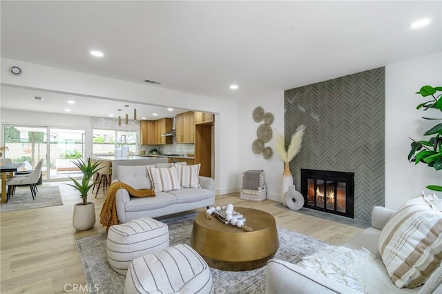 living room with recessed lighting, visible vents, light wood finished floors, and a tile fireplace