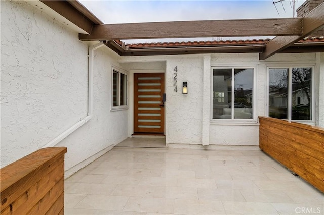 entrance to property with stucco siding and a patio