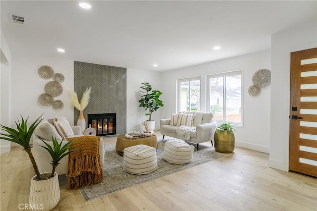 living area featuring visible vents, baseboards, a tiled fireplace, light wood-style flooring, and recessed lighting