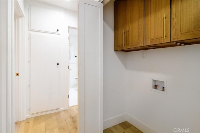 laundry area featuring cabinet space, baseboards, light wood-style floors, and washer hookup