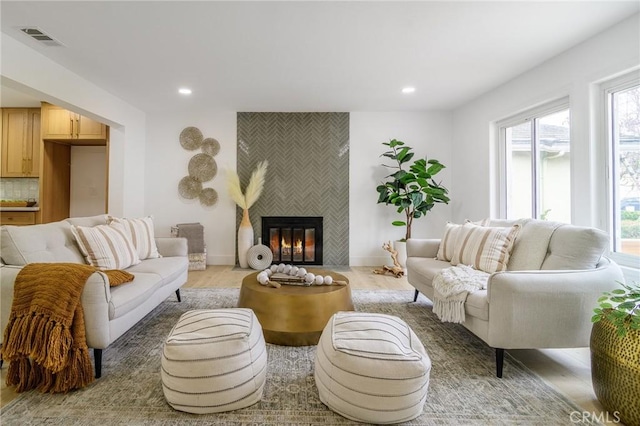 living area with light wood-type flooring, recessed lighting, visible vents, and a tile fireplace