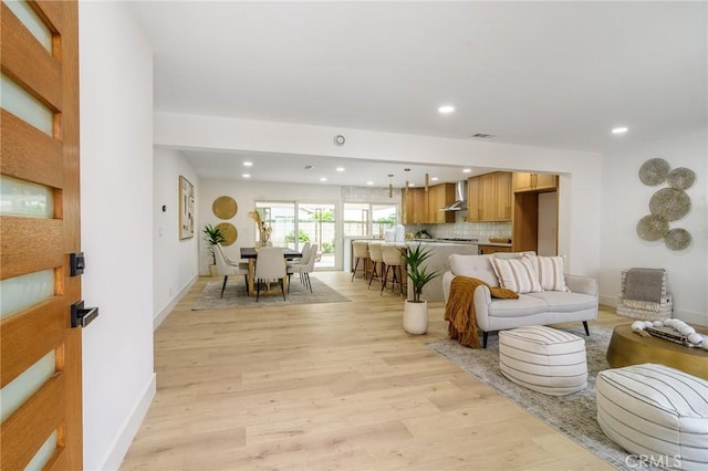 living area featuring recessed lighting, baseboards, and light wood finished floors