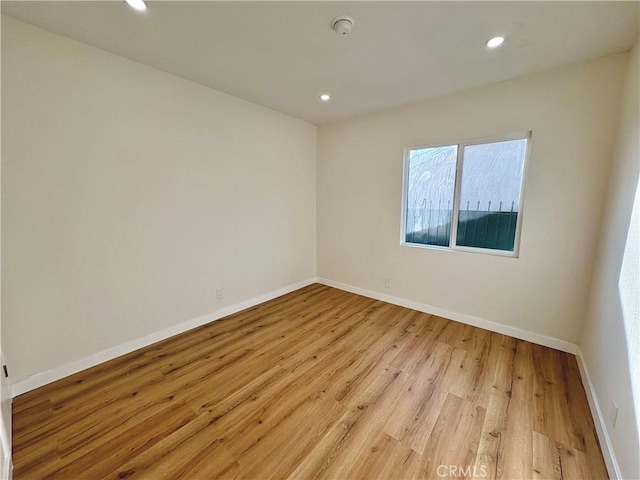 empty room featuring recessed lighting, baseboards, and light wood finished floors