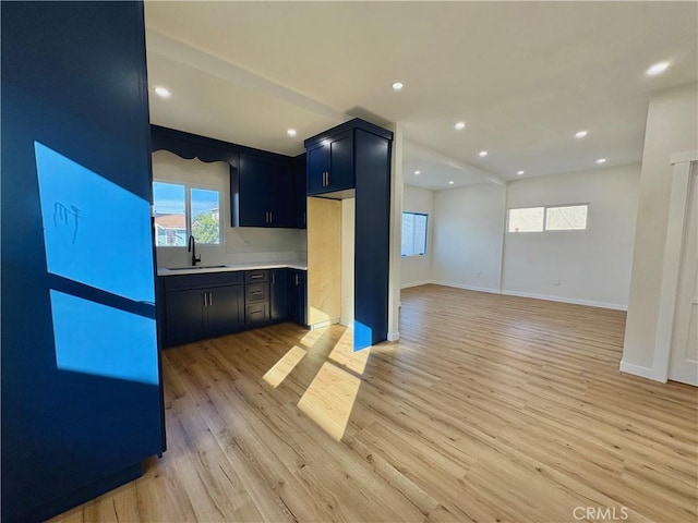 kitchen featuring a sink, recessed lighting, light wood-style floors, light countertops, and baseboards