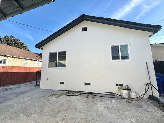 rear view of house featuring crawl space, a patio area, fence, and stucco siding