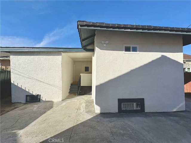 rear view of property featuring entry steps and stucco siding