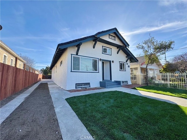 view of front of property with stucco siding, a front lawn, and fence