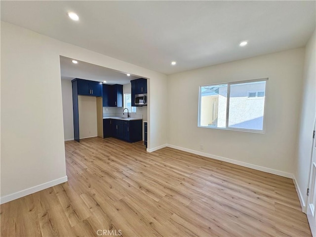 unfurnished living room featuring a wealth of natural light, recessed lighting, light wood-type flooring, and baseboards