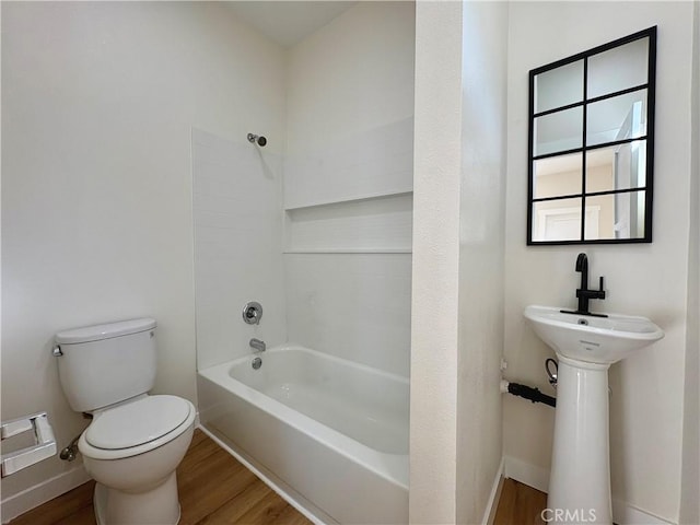 full bath with washtub / shower combination, toilet, wood finished floors, and baseboards