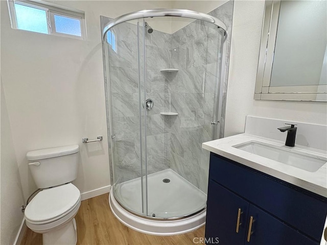 full bath featuring vanity, toilet, wood finished floors, and a stall shower