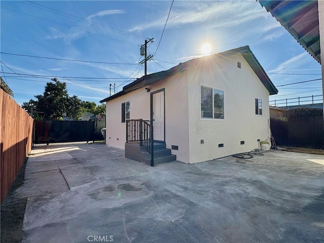 rear view of property with crawl space, a fenced backyard, stucco siding, and a patio