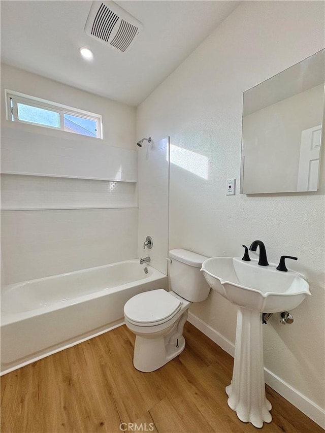 bathroom with visible vents, wood finished floors, toilet, and shower / washtub combination