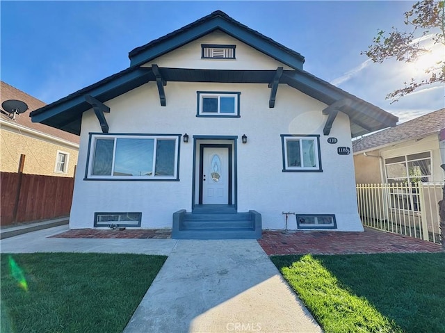 view of front of property featuring stucco siding, a front yard, and fence