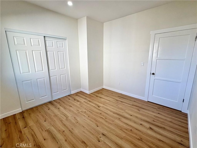 unfurnished bedroom featuring recessed lighting, a closet, baseboards, and light wood-style floors