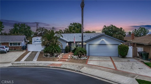 view of front of home featuring an attached garage, concrete driveway, fence, and a gate