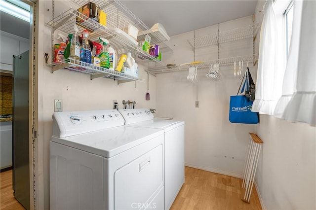 laundry area with baseboards, independent washer and dryer, laundry area, and light wood finished floors