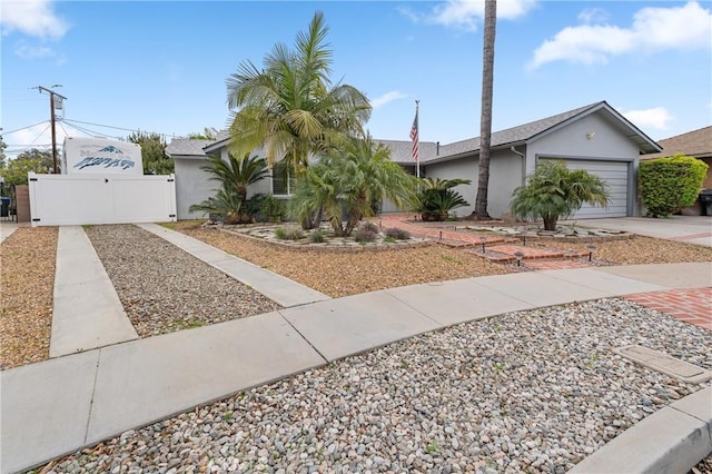 view of front of house featuring a gate, fence, stucco siding, concrete driveway, and a garage