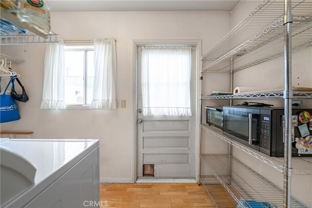 clothes washing area with washer / dryer, light wood-style flooring, and laundry area