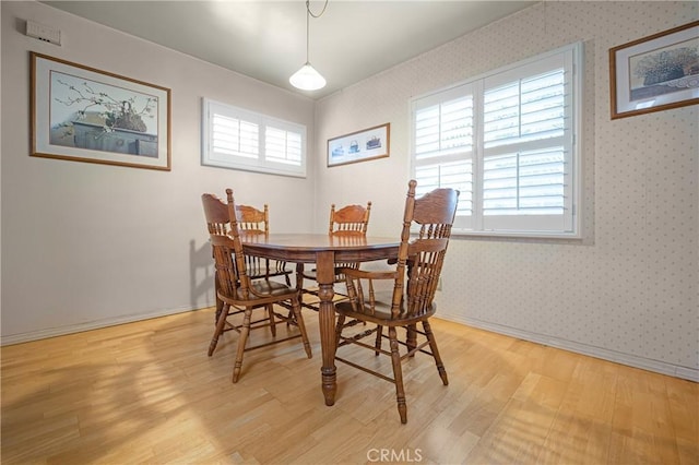 dining area with a wealth of natural light, baseboards, wallpapered walls, and light wood-style floors