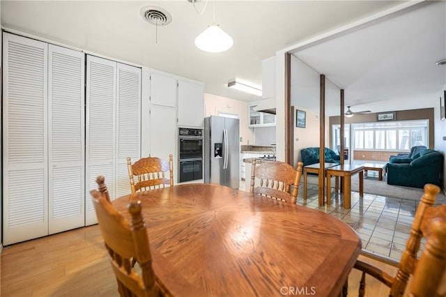 dining area featuring visible vents, light wood-style floors, and a ceiling fan