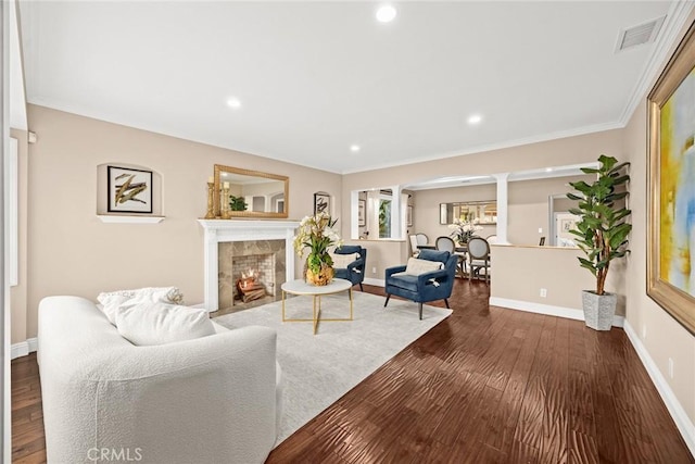 living room with visible vents, dark wood-type flooring, baseboards, ornamental molding, and a fireplace