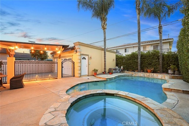 view of pool featuring a gate, a pool with connected hot tub, a patio, and fence