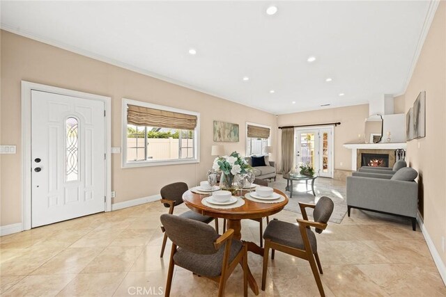 dining area featuring plenty of natural light, baseboards, and a warm lit fireplace