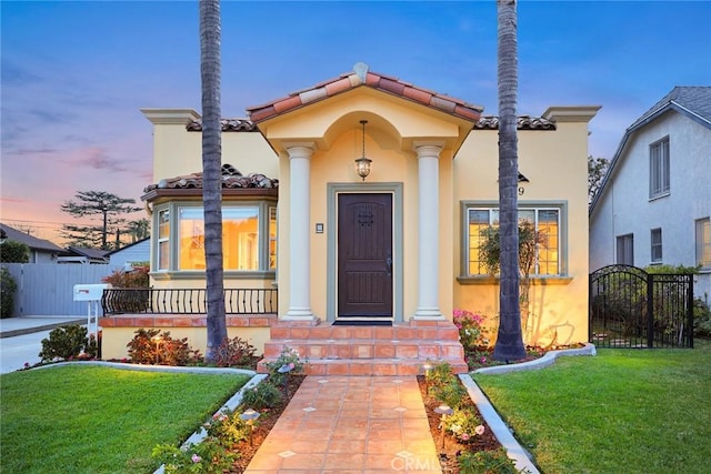 property entrance featuring a tiled roof, a yard, fence, and stucco siding