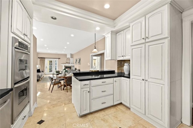 kitchen with dark countertops, open floor plan, appliances with stainless steel finishes, a peninsula, and white cabinets